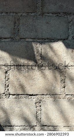 Rough concrete block wall with natural sunlight and soft shadows creating an industrial textured background. Weathered cement bricks with visible mortar lines provide an authentic construction, architecture, and urban texture concept.