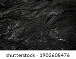 Rough dark cave stone wall texture with natural crack used for background.