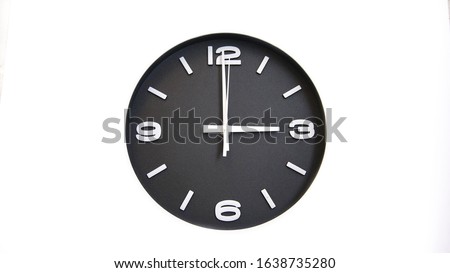 Rough and grainy black faced wall clock isolated on white background showing time at three o'clock