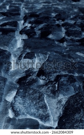 Rough granite rocks between a continuous layer of ice in permafrost 