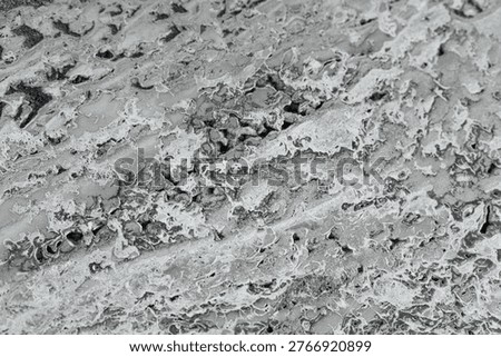 Rough gray surface texture with irregular patterns and small holes