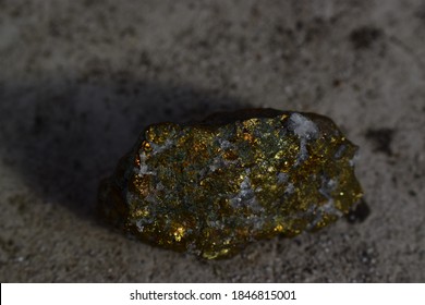 Rough mineral chalcopyrite on concrete background, a closeup of mineral stone, macro shot of shinny yellow stone, geology, healing concept - Shutterstock ID 1846815001