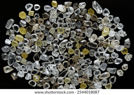Rough natural diamonds in the process of sorting by quality and color. Close up scattering uncut diamonds top view.