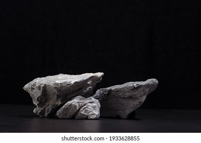 Rough natural grey stone as podium for packaging   cosmetic presentation black background  copy space 