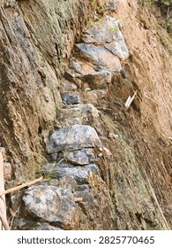 Rough natural stone steps embedded in a steep rocky hillside embankment