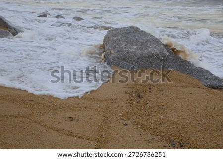 Rough ocean waves hitting rocks on the sandy shore of Dungun, Terengganu during the tropical monsoon season.