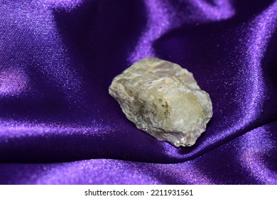 Rough spodumene aka triphane on purple satin background, a closeup of transparent yellow mineral, geology, mineralogy. - Shutterstock ID 2211931561