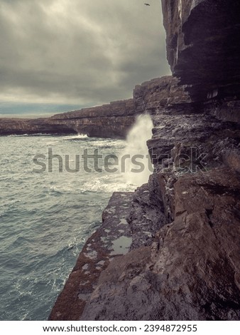 Rough stone coast and cliff of Aran Island, county Galway, Ireland. Nobody. Cloudy sky. Irish nature scene landscape. Dark and dramatic mood. Dún Aonghasa fort in the background.