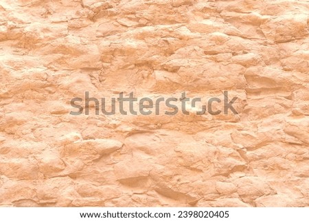 Rough stone structure wall mountain texture with shells imprinted in rock toned in trendy Peach Fuzz pantone color of Year 2024