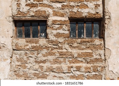Rough texture of a brick wall made of shells. Two windows in an old wooden frame. Housing problems.