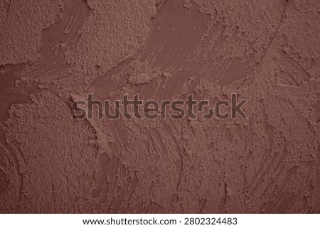 Rough texture of reddish-brown plaster with visible trowel marks.