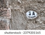 Rough Textured Cement Wall with Oval Ceramic Plaque with Number 3a and 
