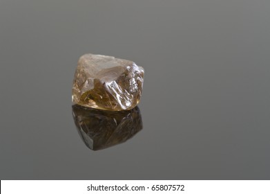 Rough Uncut Brown Diamond On A Black Reflective Surface.