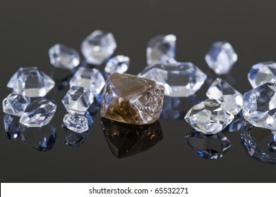 A Rough, Uncut, Brown Diamond With Quartz Rock Crystals On A Black Reflective Surface.