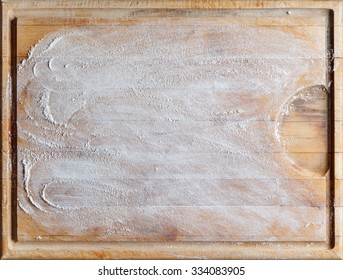 Rough wooden rectangular used cutting board background with flour directly from above