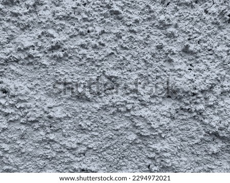 Roughcast surface. Grunge texture as background. Bumpy gray exterior wall with small frequent cracks. Rugged coarse cement or concrete rendering. Painted pebble dash. Uneven structural plaster finish.