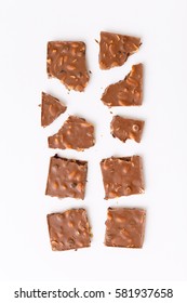 Roughly broken milk chocolate on colorful white background, top view flat lay. Minimal concept above decoration, milk chocolate food background. Chocolate Candy.
