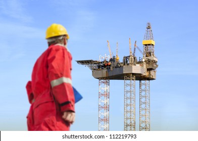 Roughneck (out of focus) looking at a huge oil rig being constructed.