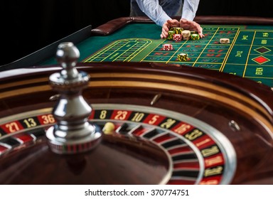 Roulette and piles of gambling chips on a green table. 