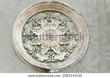 Round aged ornamental medallion on building facade