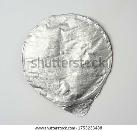 round aluminum thin lid for plastic yogurt jars, sour cream on a white background, top view