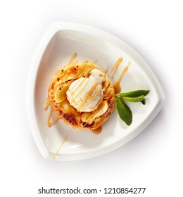 Round Apple Pie Or Tart Topped With Ice Cream Ball And Sweet Sauce In White Plate Isolated. Frozen Yogurt On Fresh Crisp Puff Or Mini Cake Decorated With Mint Leaves On A Light Background