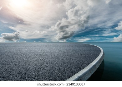 Round asphalt road platform near the lake under blue sky
