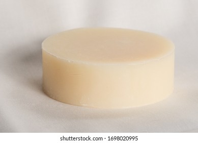 A Round Bar Of Light-colored Natural Soap On A Plain White Background.