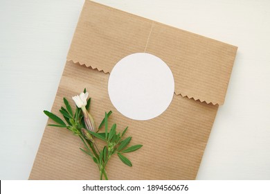 Round blank sticker mockup, circle tag mock up on kraft paper gift bag, adhesive thank you card, round product label, pink flowers.      - Shutterstock ID 1894560676