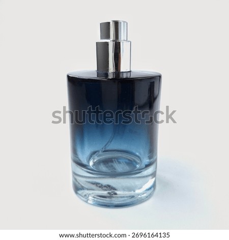 Round blue bottle with a gradient effect, transitioning from deep blue at the top to clear at the base. It features a sleek, silver metallic spray nozzle atop. The bottle has a glossy finish