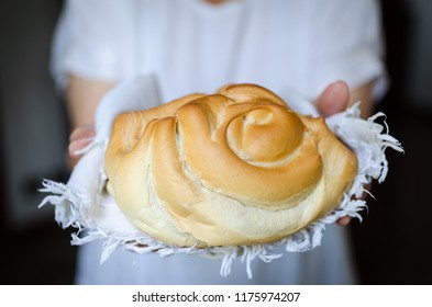 Round bread in womans hands. Baker holding a beautiful freshly baked warm bread. Rustic vintage style. Selective focus.