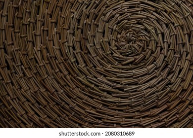 A Round Brown Rug, Hand-woven From Pine Needles, Photographed From Above With A Center In The Upper Right Corner