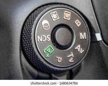 Round button for selection scene and mode on digital mirror camera, close up. Dial of programs on the modern camera, macro view.
