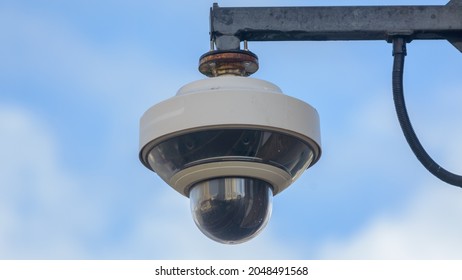 Round CCTV camera against blue sky, shallow depth of field