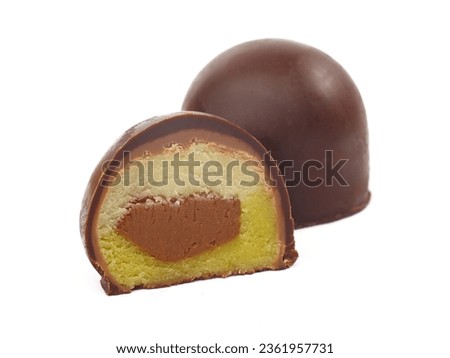 A round chocolate praline with marzipan filling cut in half, round chocolate in the background, studio shot isolated on white background