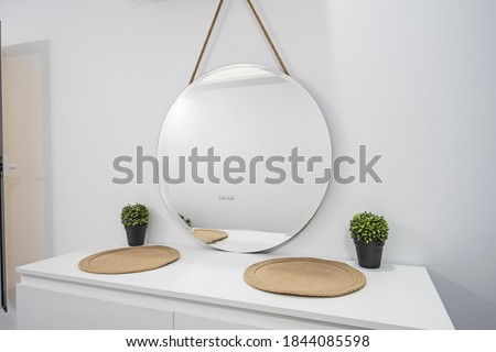 Round circular mirror haninging on wall over white dfressing table unit in luxury home residence