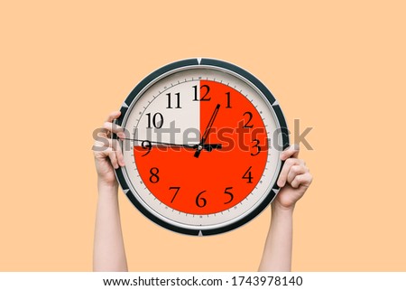 Round clock with a dial shows three-quarters of an hour. The time timer is fifteen minutes. Watch in the hands of a woman. The concept of a schedule, and assignment of time to complete work