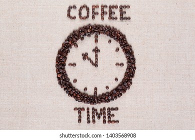 Round clock pointing eleventh hour along with coffee time words made of coffee beans on linen texture, shot close up