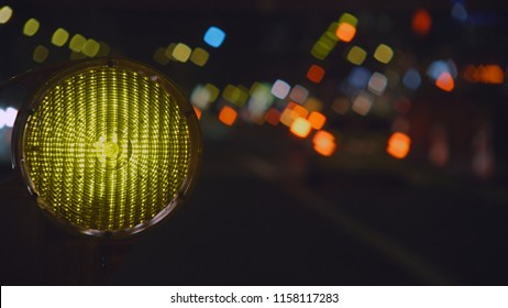 Round Construction Light With De-focused Traffic Lights In The Background At Night.