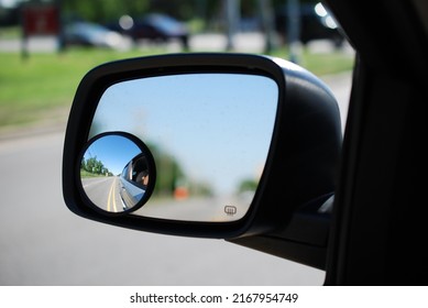 A round convex mirror (in focus) attached to a vehicle's side view mirror (rest of image, out of focus). The convex mirror provides a wider field of view .