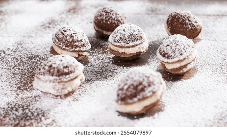 Round cookies filled with cream and dusted with powdered sugar are artfully arranged on a rustic wooden surface, inviting dessert lovers. - Powered by Shutterstock