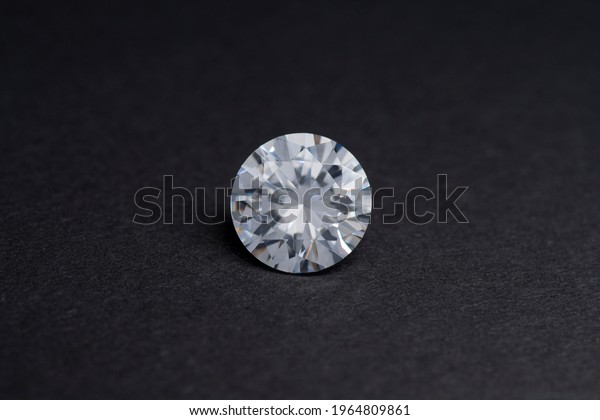 Round diamond faceted cubic zirconia, cubic\
crystalline form of zirconium dioxide (ZrO2) colorless synthesized\
material. White synthetic gemstone. Diamond imitation. Black\
isolated background.