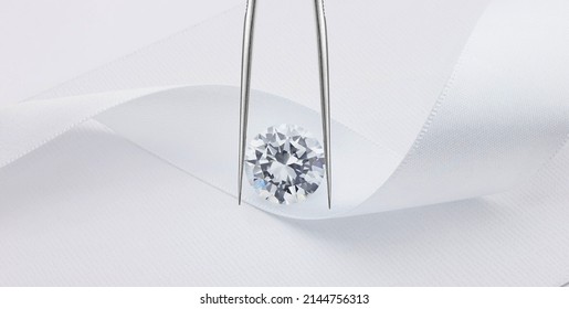 Round Diamond on White Ribbon Background Held in Tweezers - Shutterstock ID 2144756313