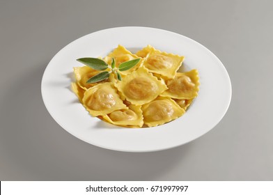 Round dish with a portion of tortelli pasta isolated on grey background
