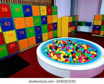 Round dry pool with colorful balls photo. Plastic bubbles for kids. Design children's game room, storage cells for personal belongings. Key-type safe cell cabinet in Entertainment center, playroom