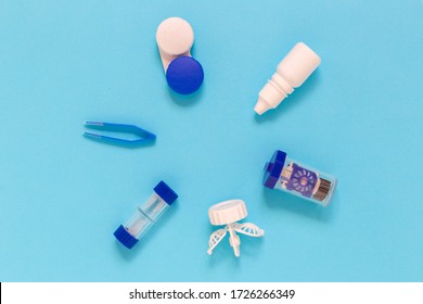 Round flat lay of vision correction lenses equipment on blue background with copy space : eye drops, containers, lenses, twizzlers 