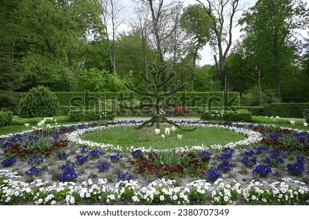 A round flower garden encircles a majestic tree at its center, creating a harmonious and captivating focal point.