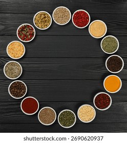 Round frame of assorted spices in white ceramic bowls over dark wooden table background with copy space, elevated top view, directly above