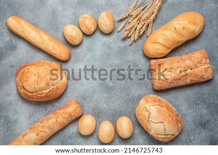 Round frame of fresh bread on a gray concrete background. Assortment of various bakery products. Top view, flat lay, copy space. Textured object, selective focus.