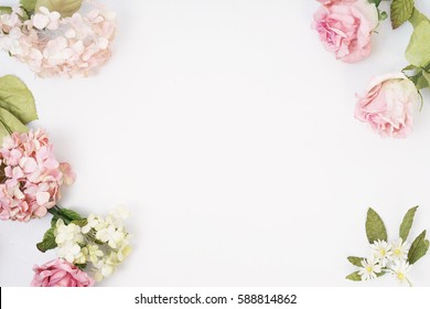 Round frame made of pink and beige roses, green leaves, branches on white background. Flat lay, top view. Wedding's background